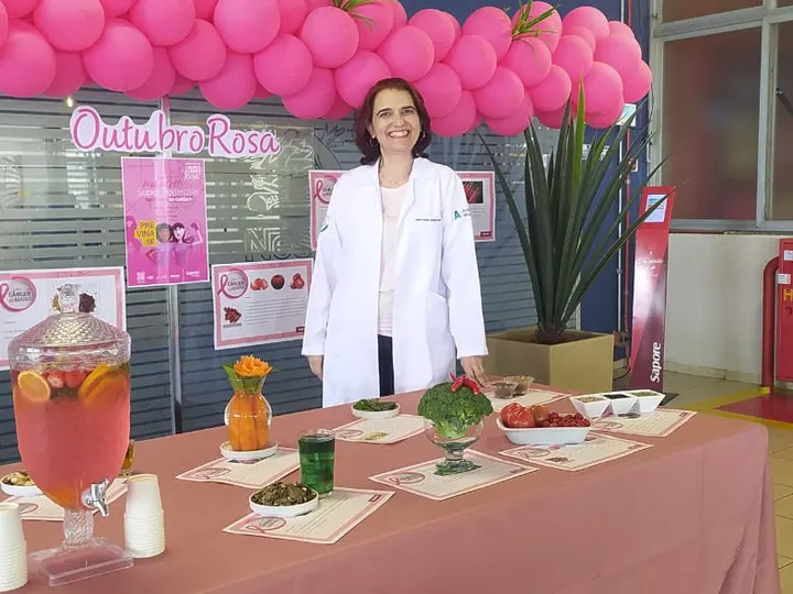 Cristina Selicani Sundfeld em estande decorado com balões rosa na ação Outubro Rosa